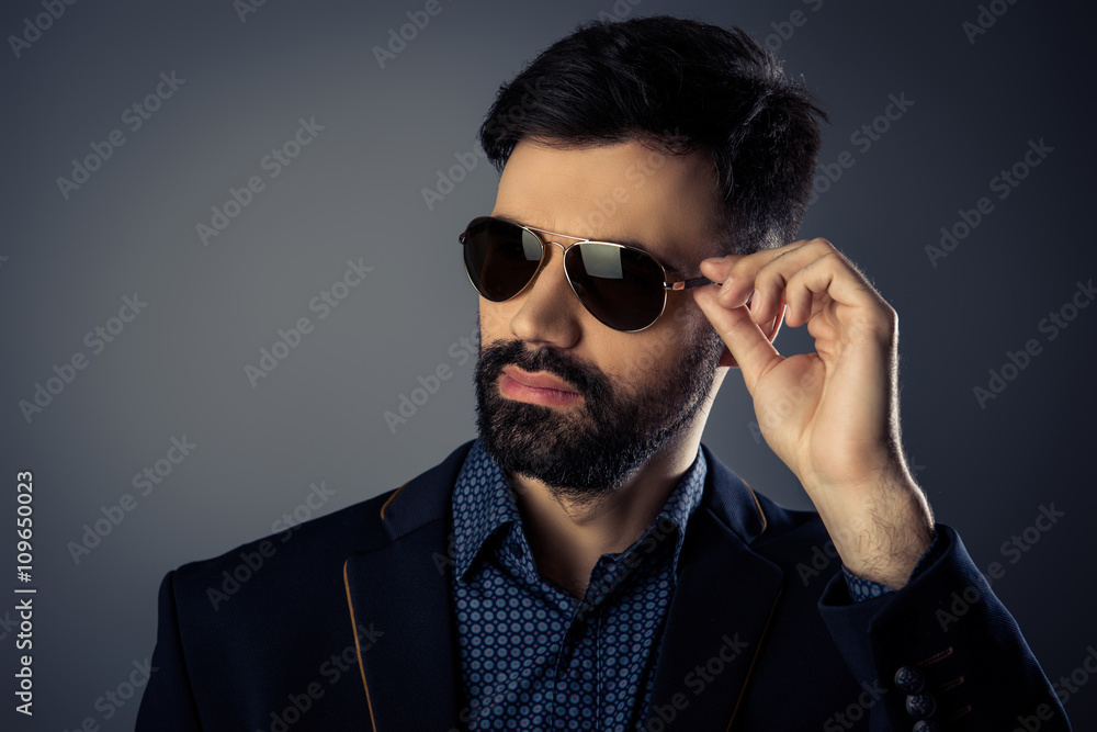 Attractive bearded man in suit touching his glasses Attractive bearded man in suit touching his glasses