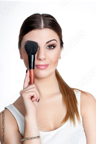 Beauty Girl make up artist with Makeup Brush. Bright Holiday Make-up for Brunette Woman with Brown Eyes. Beautiful Face. Makeover. Perfect Skin. Applying Makeup