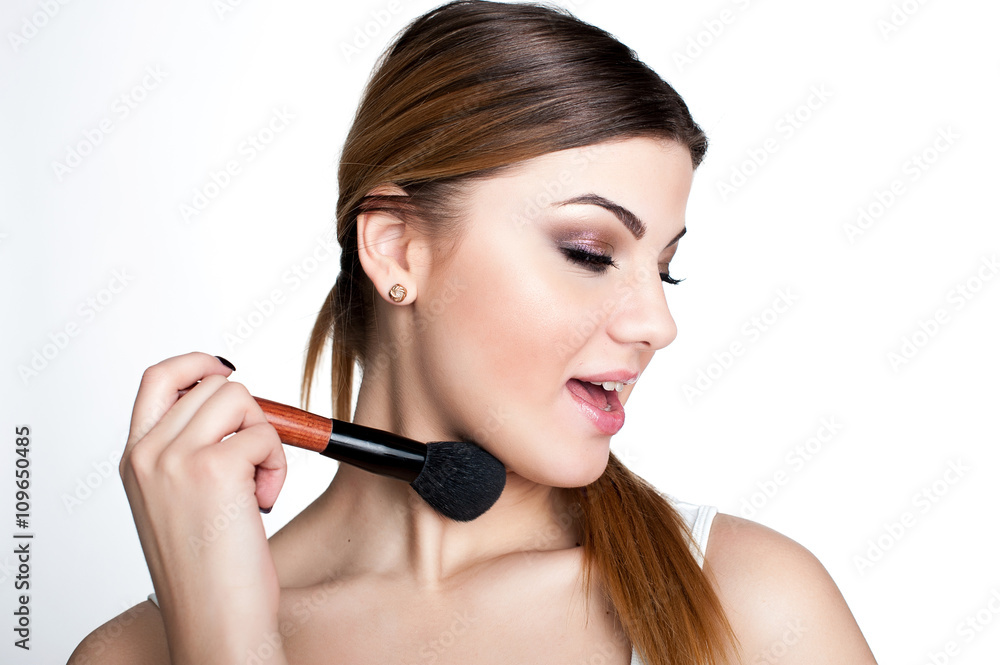 Beauty Girl make up artist with Makeup Brush. Bright Holiday Make-up for Brunette Woman with Brown Eyes.  Beautiful Face. Makeover. Perfect Skin. Applying Makeup