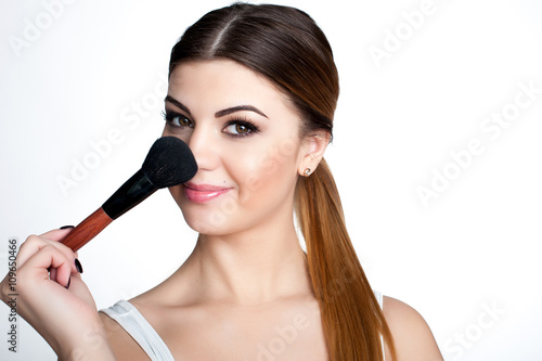 Beauty Girl make up artist with Makeup Brush. Bright Holiday Make-up for Brunette Woman with Brown Eyes. Beautiful Face. Makeover. Perfect Skin. Applying Makeup