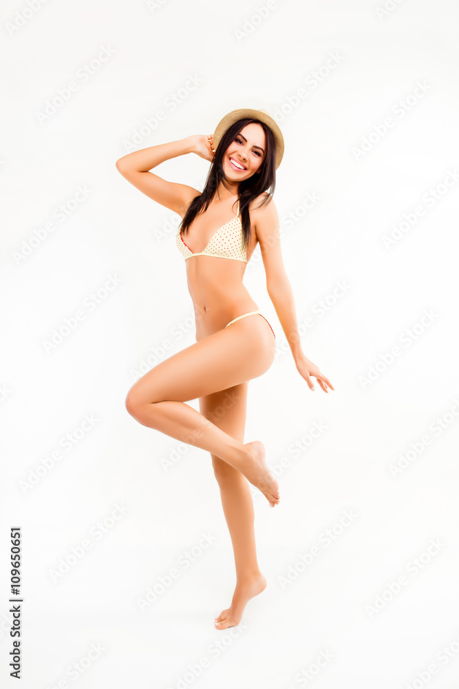 Pretty girl in hat and swimsuit dancing on white background