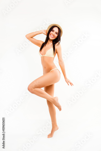 Pretty girl in hat and swimsuit dancing on white background