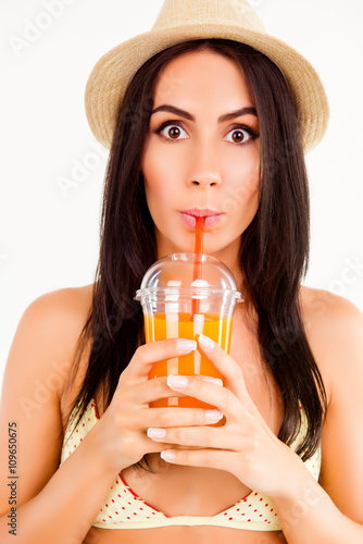 Portrait of attractive woman wearing swimsuit and hat drinking j