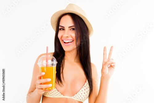 Happy woman in bikini and hat holding cocktail and gesturing wit