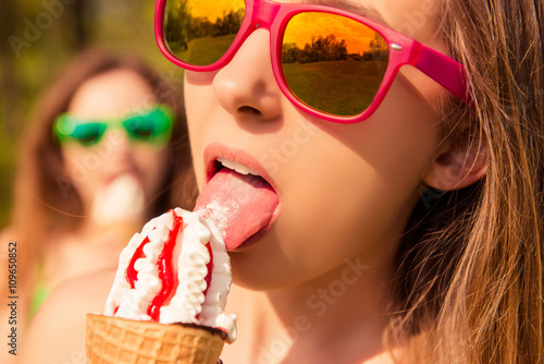 Close up portrait of beautiful girl in glasses eating ice cream