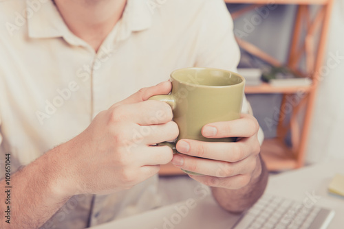 Close up photo of man's hands holding cup with tea