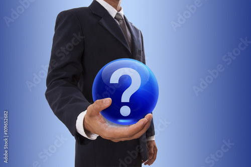 Businessman hand holding blue crystal ball with question mark icon.