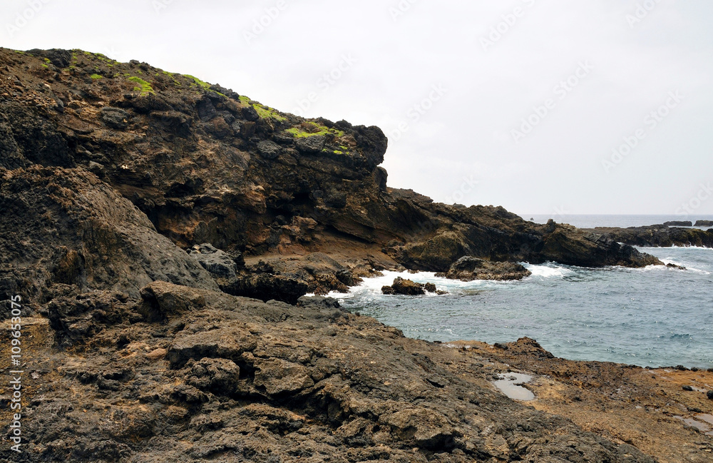 Waves crash against the rugged volcanic coastline Waves crash against the rugged volcanic coastline