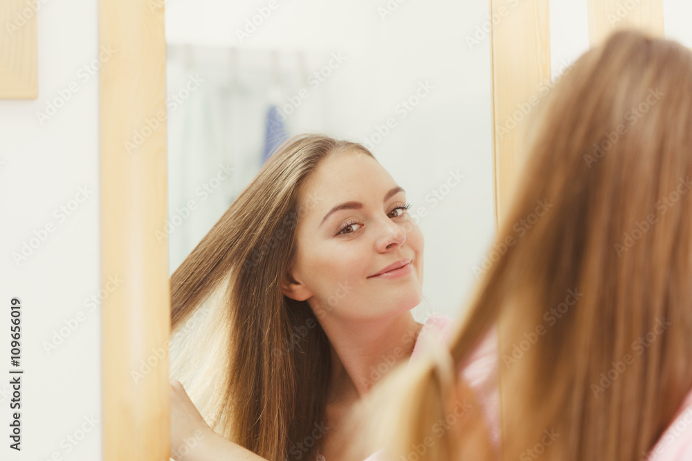 Woman combing her long hair in bathroom