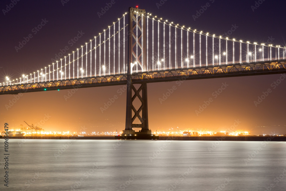 Obraz premium San Francisco-Oakland Bay Bridge, Night. Close-up of the Bay Bridge and reflected lights from Pier 14 in San Francisco.