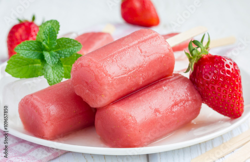 Homemade strawberry mint popsicles on a white plate