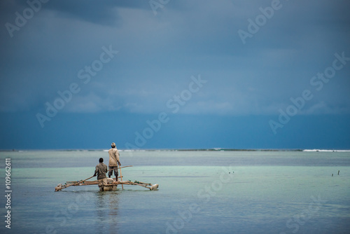 Fishermen in traditional dhow on tropical island 