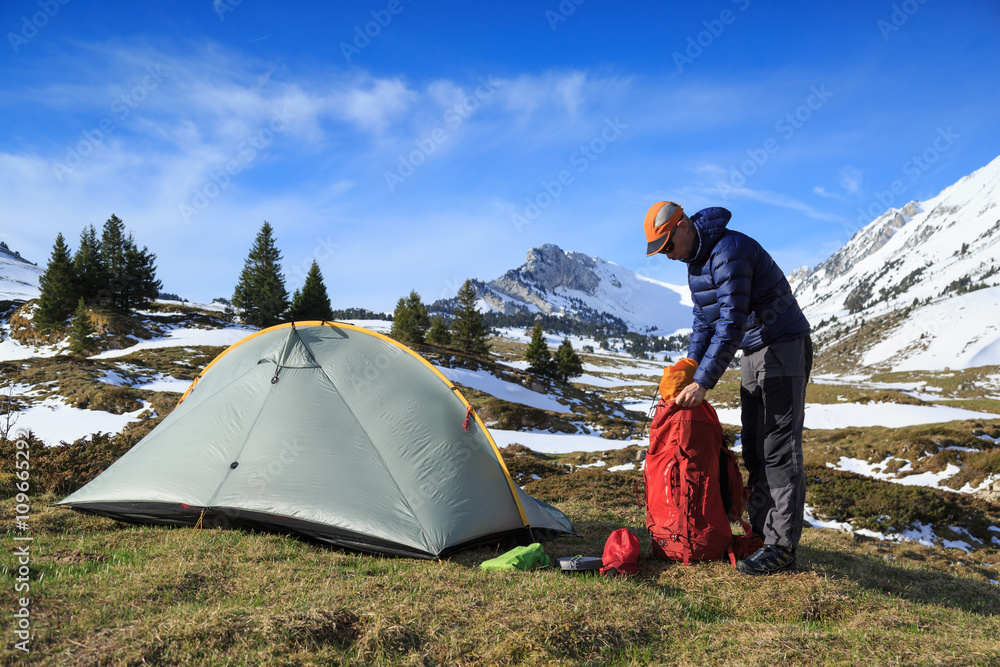 Fototapeta premium Hiker packing his backpack after camping in the mountains during springtime.