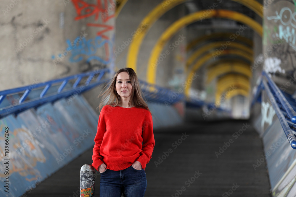 Beautiful Asian woman in red sweater and blue jeans standing on a bridge