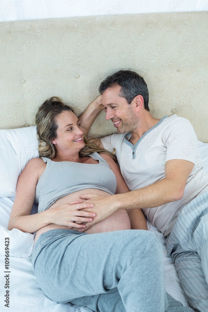 Fototapeta premium Expecting couple lying on bed and chatting