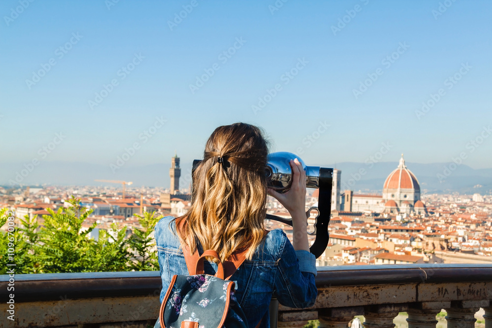 Young girl looking through a coin operated binoculars and enjoying the view of Florence, Tuscany, Italy.