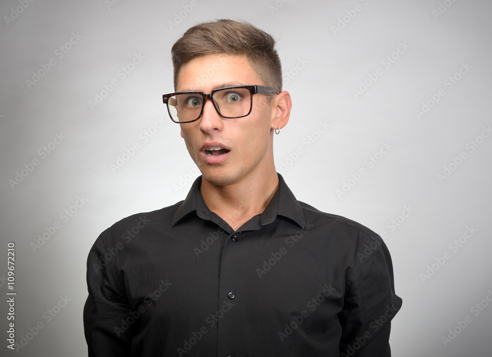 Portrait of a shocked young man in glasses