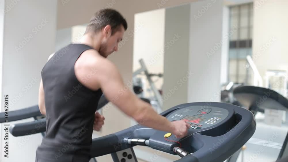 Fit athletic man is starting to run on the treadmill in the sport gym Fit athletic man is starting to run on the treadmill in the sport gym