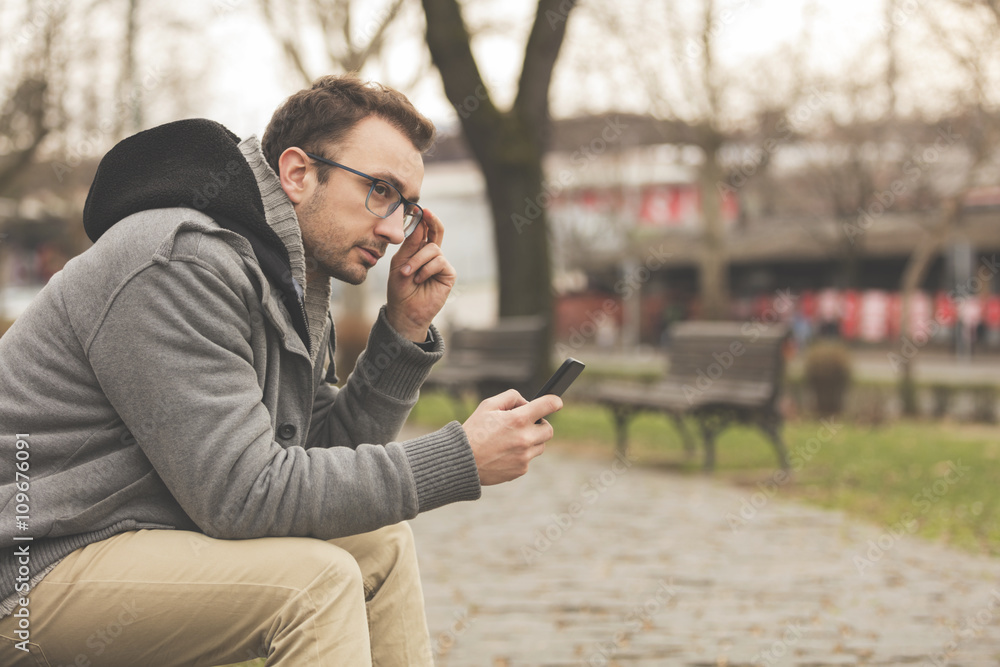 Hipster modern guy using a smartphone.
Hipster modern guy using a smartphone.