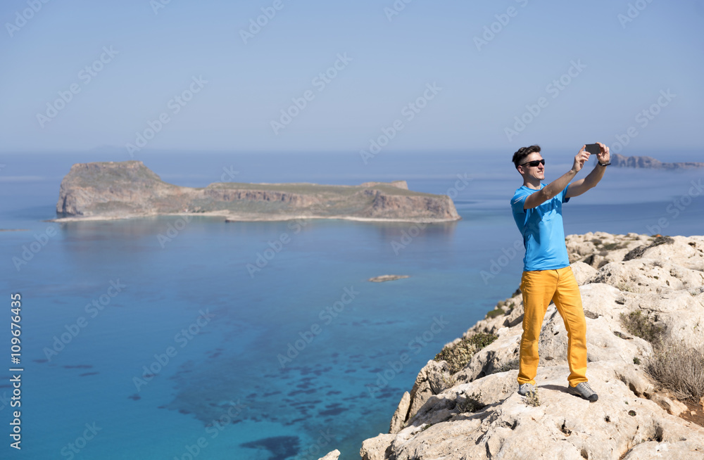 A man getting a selfie in front of the sea in the mountains