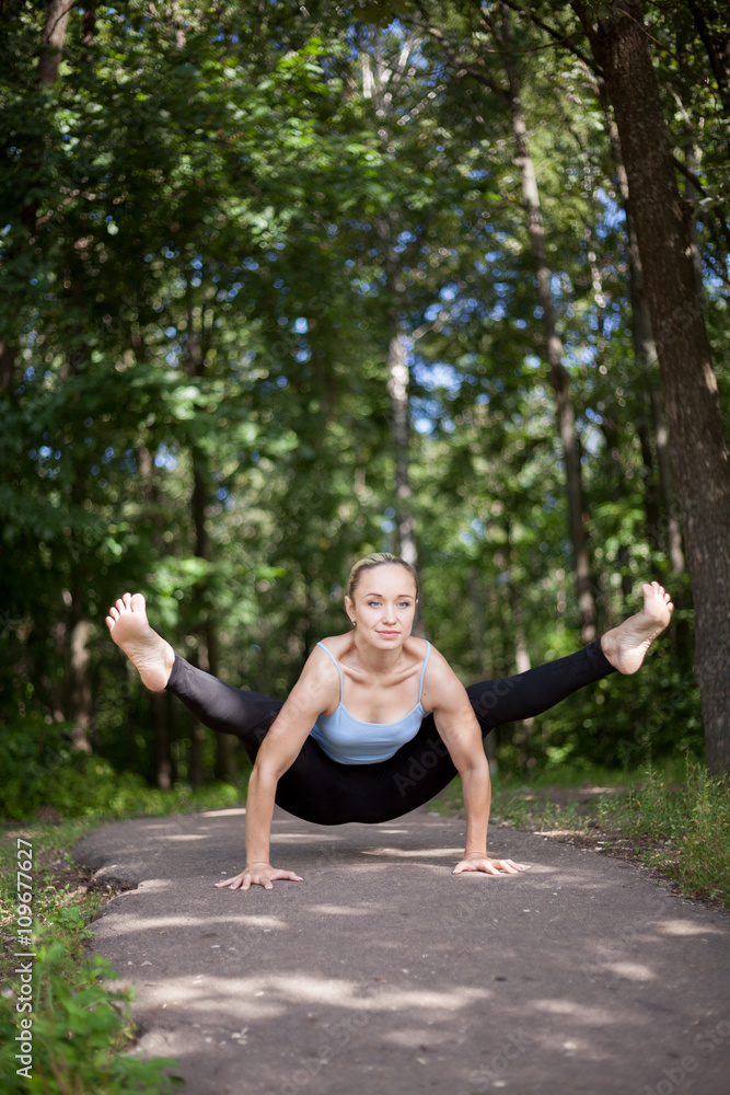 Blond young woman doing Firefly yoga posture Blond young woman doing Firefly yoga posture