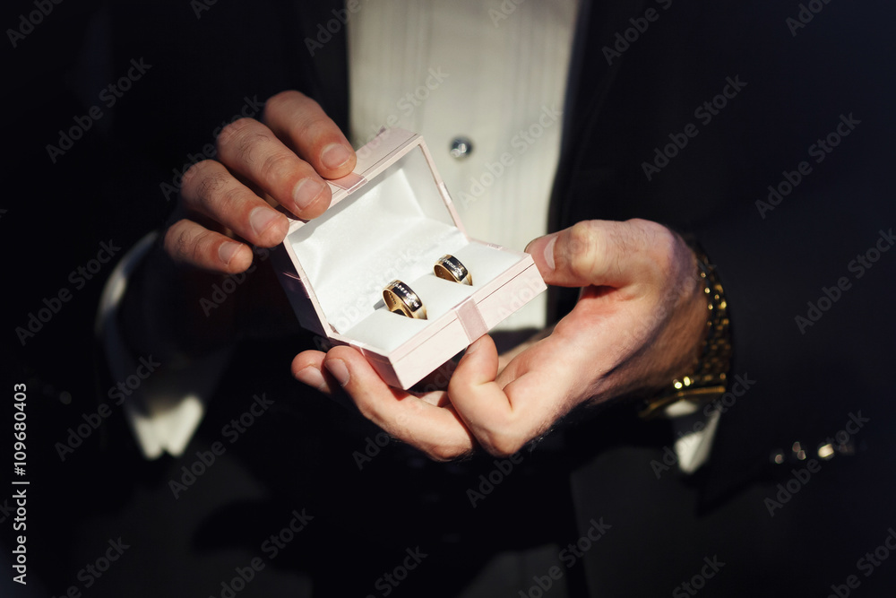 Gift box with wedding rings is opened by a man