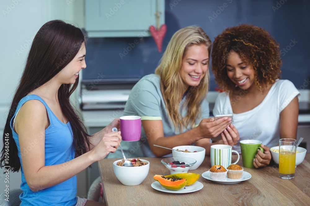 Smiling female friends using smartphone