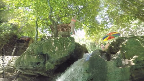 Young girl jumping of a cliff into water is very happy when she surfaces. Low angle view.
