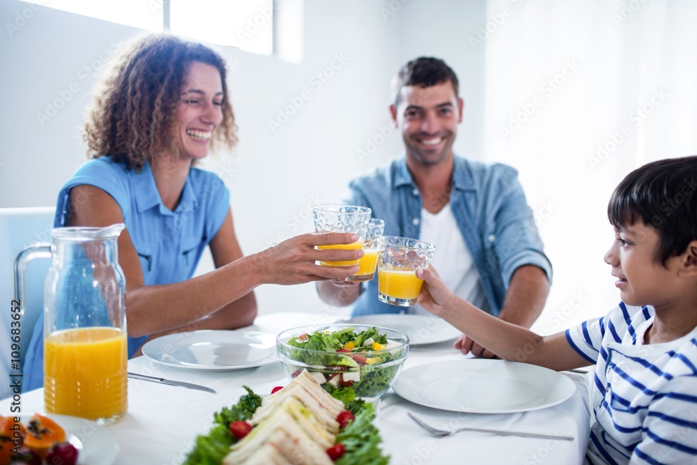 Family toasting glasses of orange juice while having breakfast Family toasting glasses of orange juice while having breakfast