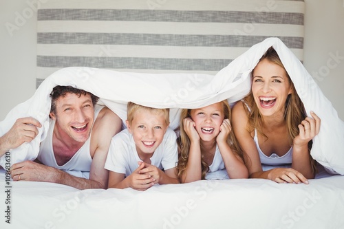 Fotografía Portrait of family covered with duvet on bed