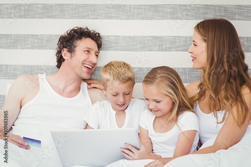 Family with laptop on bed