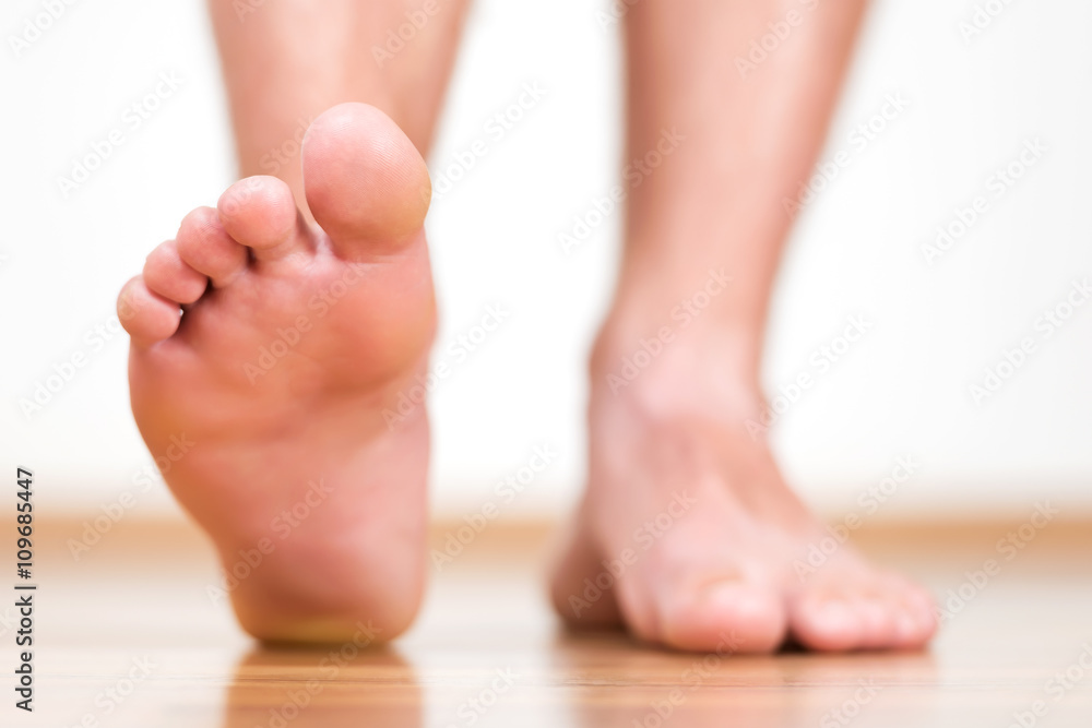 Healthy male feet stepping over home-like background Healthy male feet stepping over home-like background