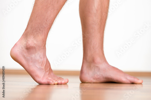 Pair of clean male feet without any illness making a step. © koszivu