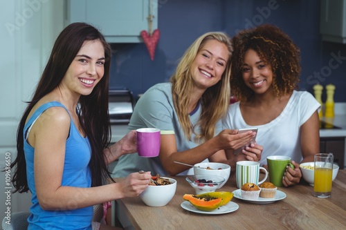 Portrait of smiling female friends using smartphone