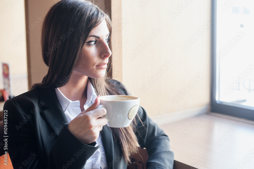 Young woman drinking coffee looking out the window Young woman drinking coffee looking out the window