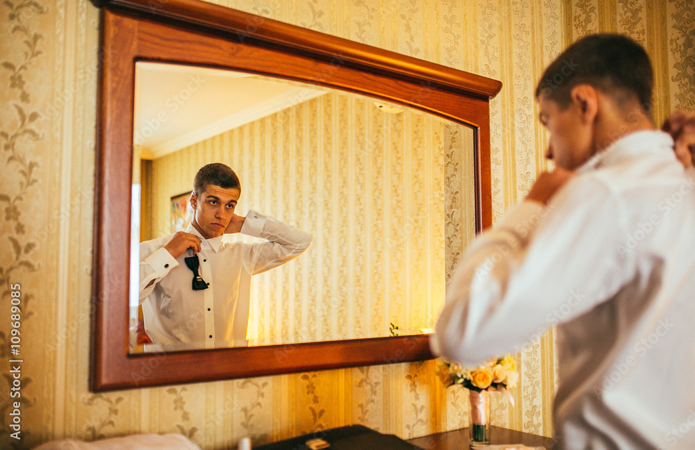 Groom in the morning on the wedding day buttoning cuffs his hands on his suit Groom in the morning on the wedding day buttoning cuffs his hands on his suit