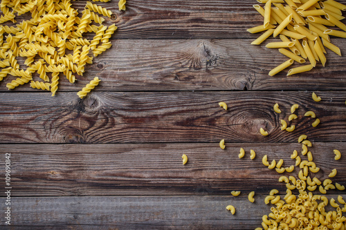 Mixed dried pasta selection on wooden background.
