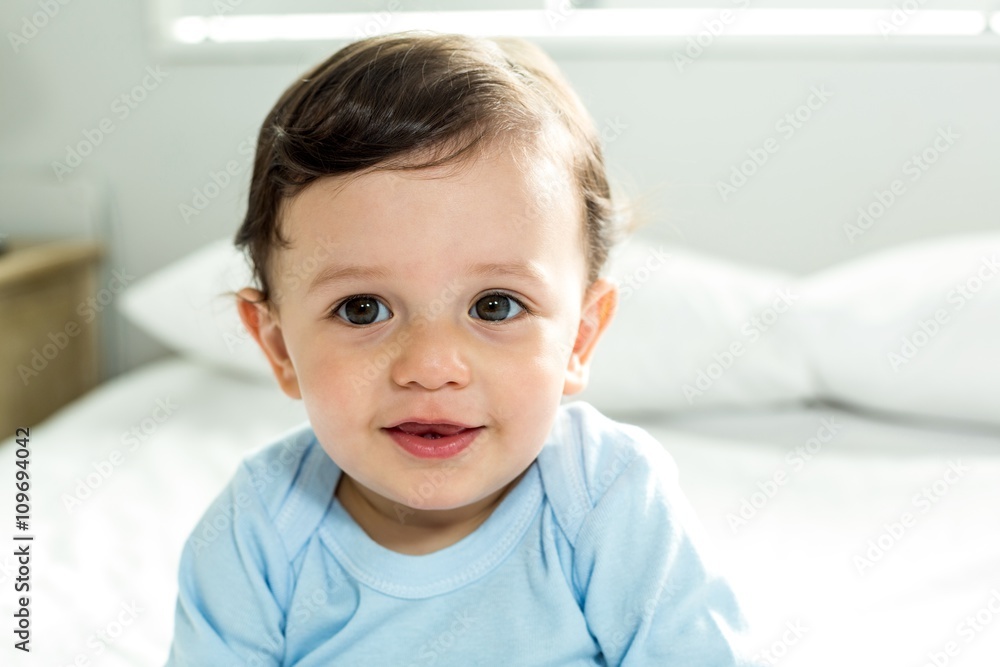 Portrait of cute baby boy sitting on bed