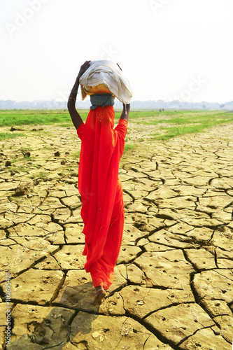 Women carrying baskets on dry ground, India