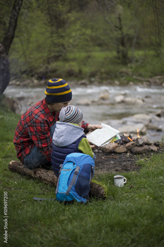 Father and son sitting near a campfire at the campsite and are l