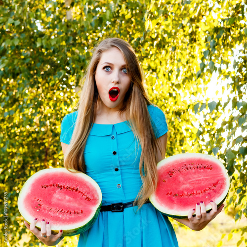 Beautiful blonde girl holding two halves of a sliced watermelon photo