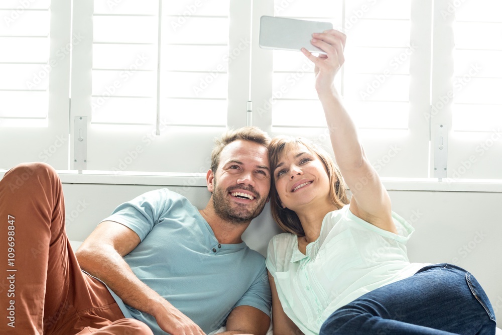 Couple taking selfie while relaxing on bed
