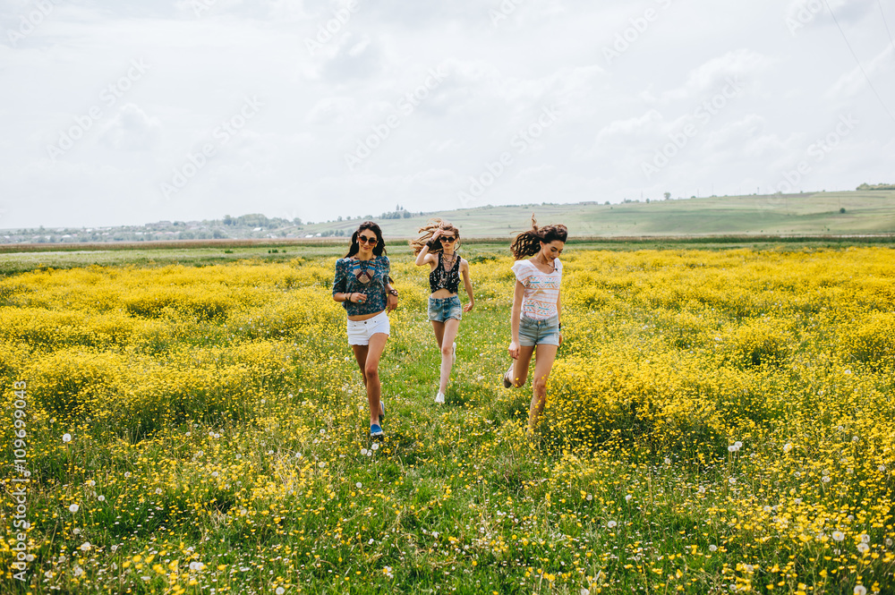 3 beautiful hippie girl in a field of yellow flowers