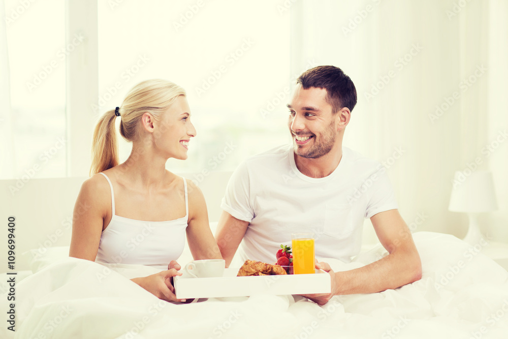 happy couple having breakfast in bed at home