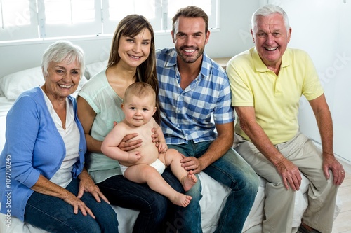 Happy multi-generation family sitting on bed at home