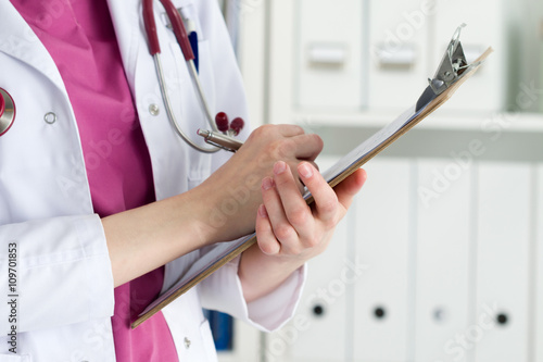 Close up view of female doctor hands holding clipping pad photo