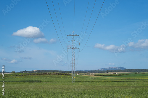 High voltage transmission tower and cable line in the countryside under a blue sky