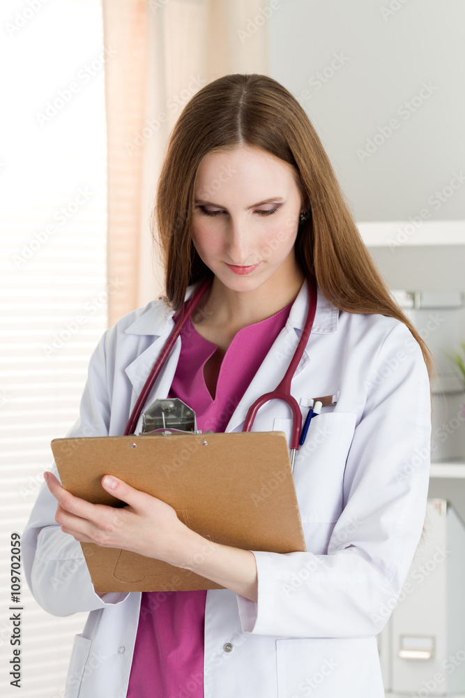 Portrait of young female doctor holding clipping pad Portrait of young female doctor holding clipping pad