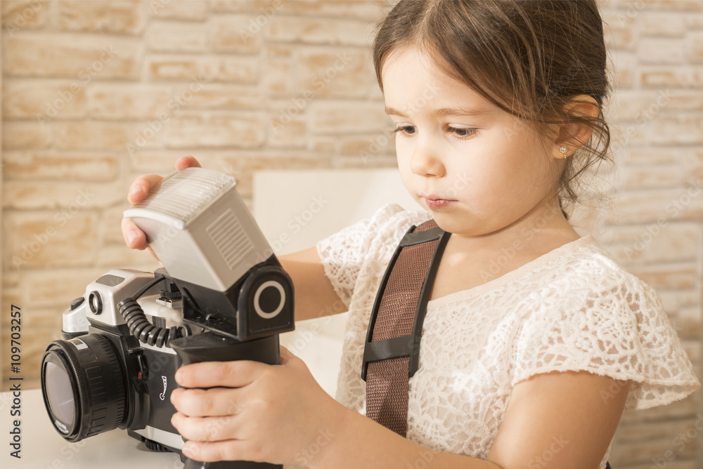 Young beautiful little girl photographer holding old vintage film photo camera. Children's play. Art or creativity concept. 