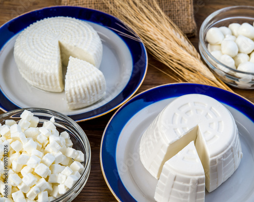 Tzfat cheese, wheat, cottage cheese, and mozzarella balls on wooden deck for Shavuot celebration. 